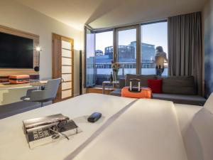 a hotel room with a bed and a living room at Novotel Wien City in Vienna