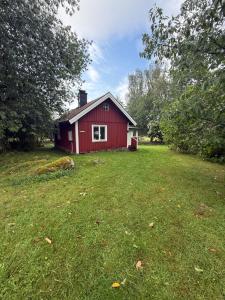 a red house in the middle of a field at Horsvik - Hagstugan in Studsvik