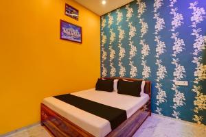 a bedroom with a bed with a blue and yellow wall at SPOT ON Surya Hotel in Handiā