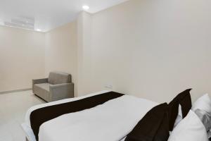 a white bedroom with a bed and a chair at Hotel O RB Delight in Karīmnagar