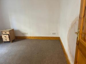 an empty room with a wooden door and a dresser at Brighton Heights With Sea Views in Brighton & Hove