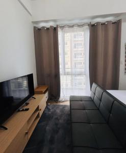 a living room with a couch and a television at 36 Bright Studio Getaway in Iloilo City