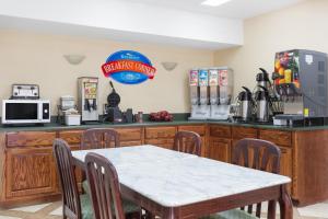 a dining room with a table and a kitchen at Baymont by Wyndham Anderson Clemson in Anderson