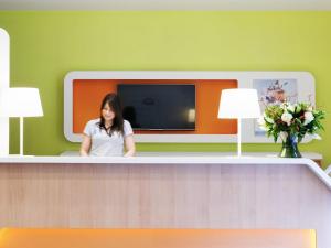 a woman sitting at a counter in a waiting room at ibis budget Antwerpen Centraal Station in Antwerp