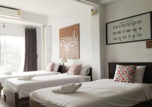 a room with three beds with white sheets at Yoont Hotel in Ban Khun Yuam