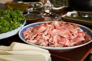 a table topped with a bowl of meat and vegetables at 森吉山温泉小さな森の湯 in Osarizawakōzan
