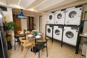 eine Waschküche mit Waschmaschinen sowie einem Tisch und Stühlen in der Unterkunft Cozy Apartment- Free for Laudry, Gym Private, CoffeBar -Desk for working- 2mins to Train St in Hanoi