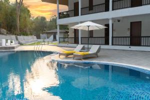 a swimming pool with two lounge chairs and an umbrella at Aranyam in Rishīkesh