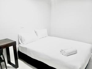 a white bed in a room with a table at X Mitr Inn Khaosan Road มิตร อินน์ ตรอกข้าวสาร in Bangkok