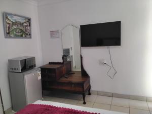 a living room with a microwave and a television on a wall at Best Enough Guesthouse in Pretoria