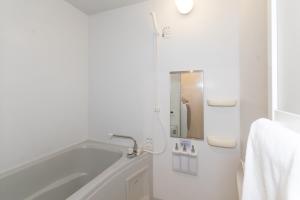 福岡市にあるレトア博多駅南の浴槽と鏡のある白いバスルーム