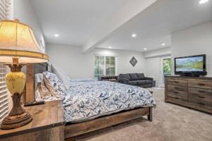 ein Schlafzimmer mit einem Bett mit einer Lampe und einem TV in der Unterkunft Forest Retreat with Decks, Game Room & Walk to Lake in Lake Arrowhead