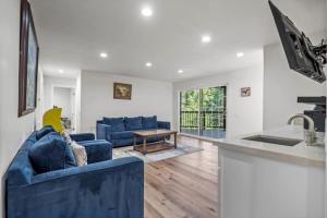 ein Wohnzimmer mit blauen Sofas und eine Küche in der Unterkunft Forest Retreat with Decks, Game Room & Walk to Lake in Lake Arrowhead