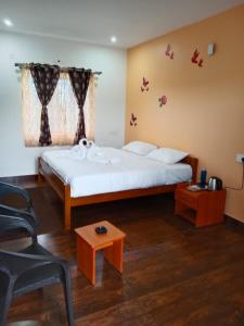 a bedroom with a bed with a window and a table at diamond hill view cottage in Ooty