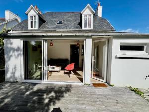 a white house with a red chair on a patio at Jolie maison de familial au cœur de Carantec - TY LAOUEN in Carantec