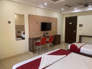 Una habitación de hotel con dos camas y un escritorio con televisión. en Townhouse Punnami Riverview Formerly Vihaan Square, en Vijayawāda 11 fotos más