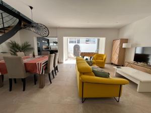 a living room with a dining table and yellow chairs at Maison rénovée avec patio plage à pied in Saint-Jean-de-Luz