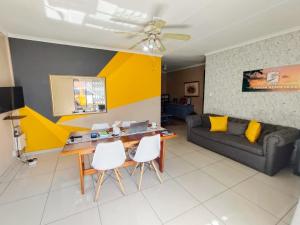 ein Wohnzimmer mit Sofa, Tisch und Stühlen in der Unterkunft Tokelo Guesthouse Emalahleni in Witbank