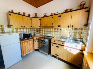 cocina con armarios de madera, fogones y fregadero en Casa DaRin, en Vigo di Cadore