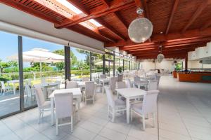 a restaurant with white tables and chairs and windows at All Senses Ocean Blue Sea Side Resort - All Inclusive in Kremasti
