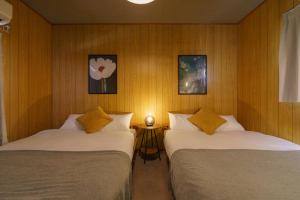 two beds in a room with wooden walls at 10min Nagoya 18ppl 4BR 50min Centrair 8Beds 2Futon in Nishi-biwashima