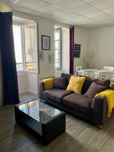 a living room with a brown couch and a glass table at Casa Cocon -Charmant T3-plages, centre ville- 4 personnes in Pornic +6 photos