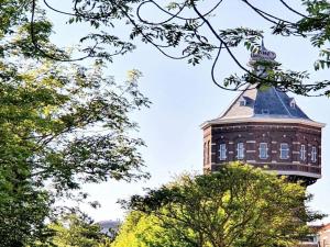 a building with a tower with trees in the foreground at Renovated luxury water tower within walking distance of the beach boulevard in Vlissingen