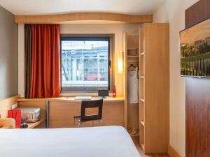 Un dormitorio con una cama y un escritorio y una ventana. en Ibis Madrid Alcobendas, en Alcobendas