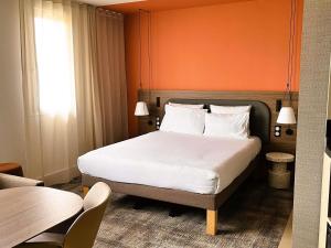 a bedroom with a large bed with an orange wall at Novotel Suites Clermont Ferrand Polydome in Clermont-Ferrand