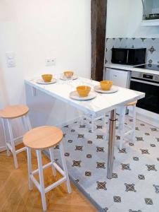 a kitchen with a white table and two stools at Lemullier de Bressey - Hôtel particulier au coeur de Dijon in Dijon