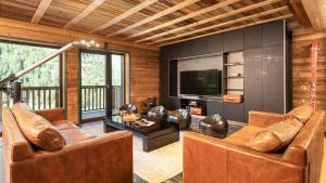 sala de estar con muebles de cuero y TV en Black Diamond - Chalet Babylon, en Les Brévières