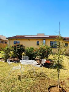 Zwei weiße Stühle stehen im Gras vor einem Haus in der Unterkunft Tokelo Guesthouse Emalahleni in Witbank
