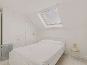 a white bedroom with a bed and a skylight at Appartement avec piscine commune pour 4 in Guérande