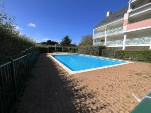 a swimming pool in front of a building at Appartement avec piscine commune pour 4 in Guérande