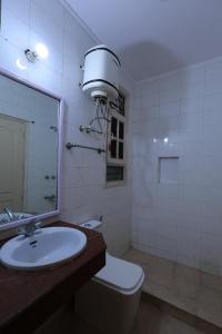 a bathroom with a sink and a toilet and a mirror at Imperial Home Stayz in Gurgaon