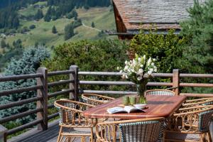 a wooden table with a vase of flowers on a balcony at Chalet Jenna Verbier - by EMERALD STAY in Verbier