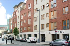 un grand bâtiment en briques avec des voitures garées devant lui dans l'établissement Foley Street Apartment, à Dublin