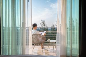 a man sitting in a chair reading a paper on a balcony at The Kaset, Hua Hin in Hua Hin +62 photos