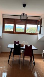 una sala da pranzo con tavolo, sedie e finestre di Aldea Bricia 6 a Posada de Llanes Altre 7 foto
