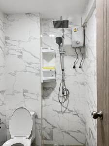 a bathroom with a toilet and a white marble wall at Patong Vacation Rentals - Located in the Heart of Patong, Studio Apartments walking distance to the beach, King Bed, Kitchen, Private Bathroom, Seating Area, 65" Smart TV with Free WIFI in Patong Beach