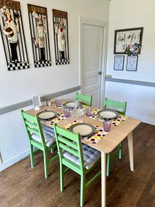 a dining room table with green chairs and a table with plates at Renovated French Country House for Six - A Home for Your Next Holiday in Hercé