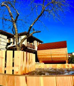 a wooden fence with a tree in front of a house at Vila Martina in Smilyan +8 photos