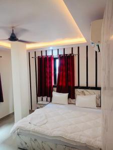 a bedroom with a large bed with red curtains at Hotel Tara ji Bliss in Haridwār