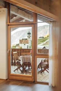 a sliding glass door with a table and chairs on a balcony at Oberegghof Ferienwohnung Hahnenkamm in Rifiano