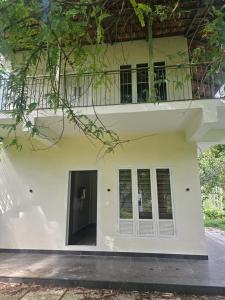a white building with a balcony on top of it at Hamai Grand Home Stay in Ambalavayal