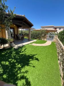 a yard with green grass and a stone wall at Casa Villetta Vacanze Budoni in Budoni
