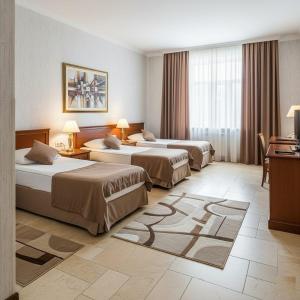 a hotel room with three beds and a television at Baku Khatai Central Hotel in Baku