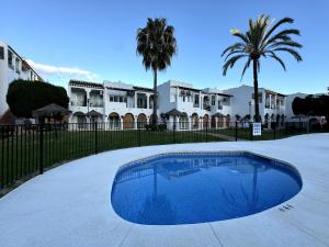 a large blue swimming pool in front of some houses at Apartamento Marinas de Nerja in Nerja