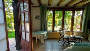 a living room with windows and a table and chairs at Les 2 Ginkgos à 5 minutes de Beauval in Seigy