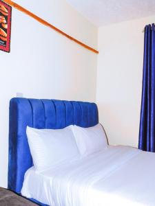 a bed with a blue headboard and white pillows at Stivo apartment in Nakuru